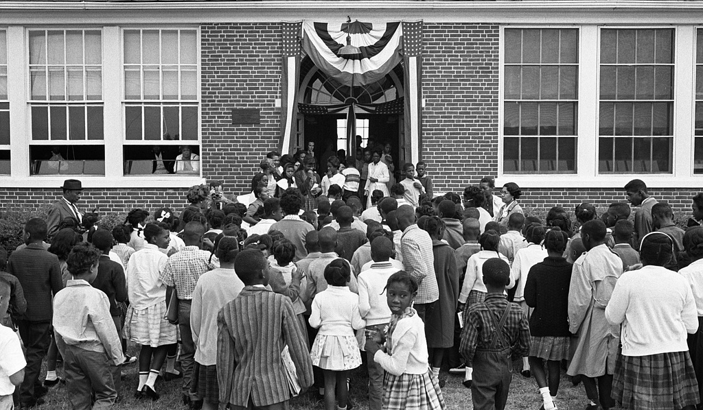 An image of the front of Moton High School with lots of students outside and banners above the doors